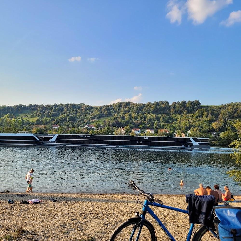 A bicycle on a sandy beach with a river and a cruise ship in the background.